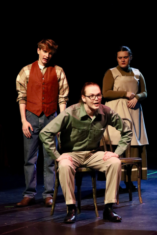 three people in costume with one in the front sitting in a chair.